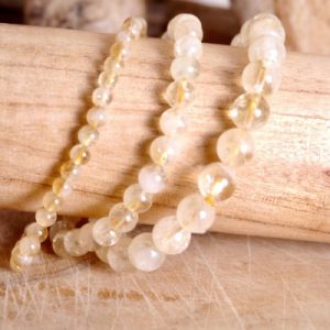 Bracelet en pierre naturelle de citrine présentés sur un rondin de bois et fond bois. Il y a 3 modèles avec des tailles de perles différentes : 8mm, 6mm et 4mm.