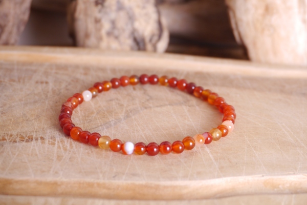Bracelet en pierre naturelle cornaline de couleur orange perles de taille 4mm posé sur une planche de bois