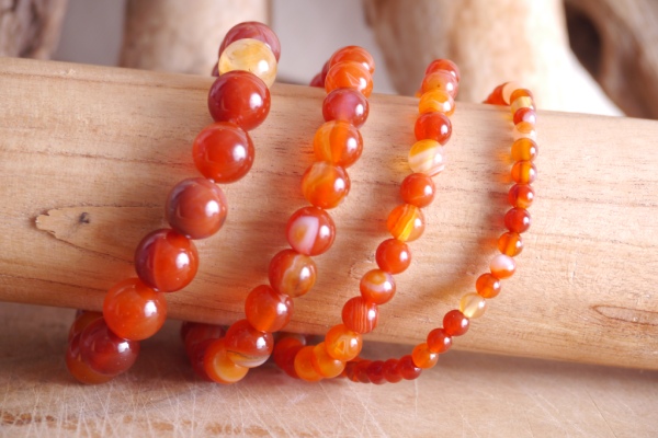 Bracelet en pierre naturelle cornaline de couleur orange sur rondin de bois. En 4 tailles 10mm, 8mm, 6mm et 4mm