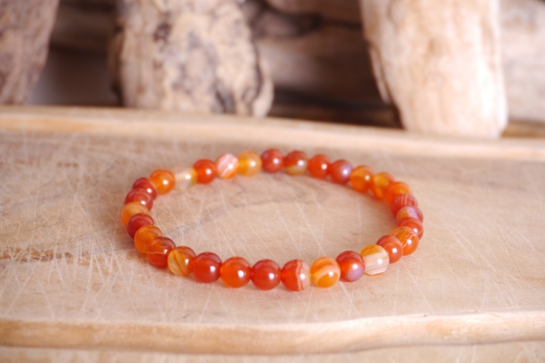 Bracelet en pierre naturelle cornaline de couleur orange perles de taille 6mm posé sur une planche de bois