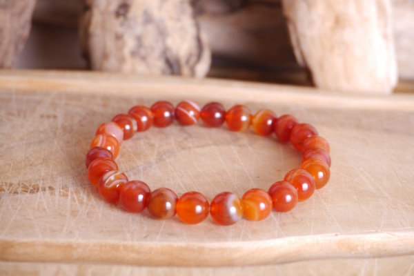 Bracelet en pierre naturelle cornaline de couleur orange perles de taille 8mm posé sur une planche de bois