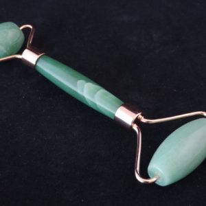 Roller de massage en aventurine sur fond noir. Il présente un petit rouleau pour les yeux et la bouche et un grand rouleau pour le reste du visage