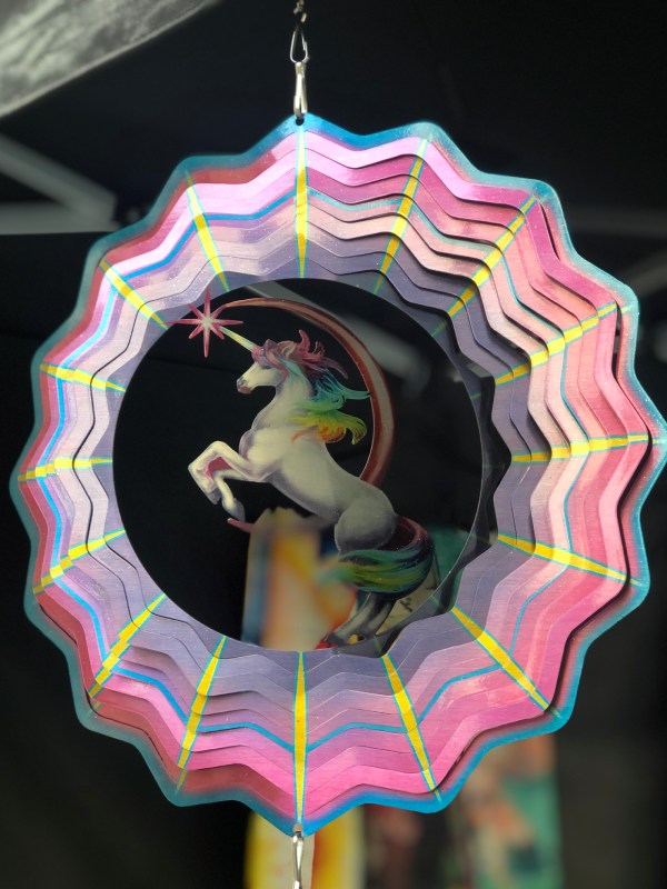 Wind spinner déco licorne. La forme extérieure ressemble à une étoile. Les couleurs vont du blanc au rose en passant par le bleu