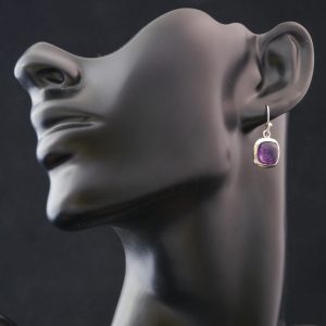 Boucles d'oreilles pendante en argent et améthyste de forme carré accrochées a l'oreille d'un buste noir