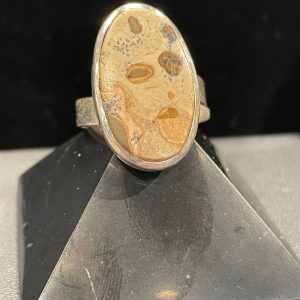 Bague argent réglable et pierre jaspe océan sur fond noir posée sur une pyramide noire, prise de face