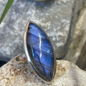 Bague en argent et labradorite forme navette. Bague posée sur une pierre blanche. Photo prise de face