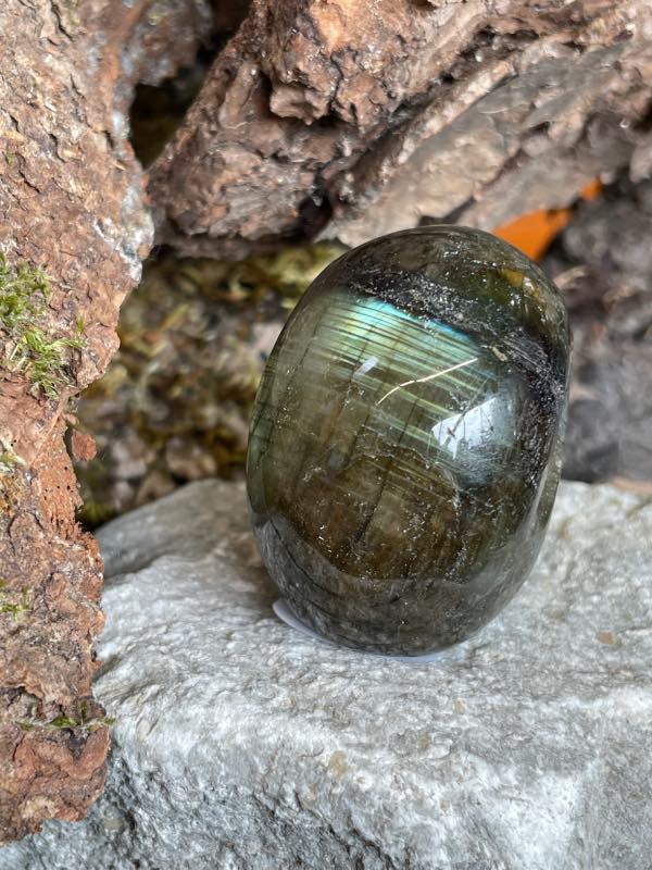 Crâne en pierre labradorite posée sur une pierre blanche. Photo prise de l’arrière