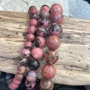 Bracelet rhodonite perles 10 et 8 et 6mm. Bracelet enfilé sur un bois flotté, photo prise sur fond naturel en pierres